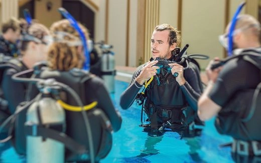 A scuba instructor teaching his students in a pool